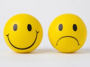 Dos caras esféricas amarillas, una sonriente y una triste