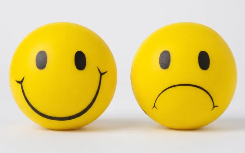 Dos caras esféricas amarillas, una sonriente y una triste